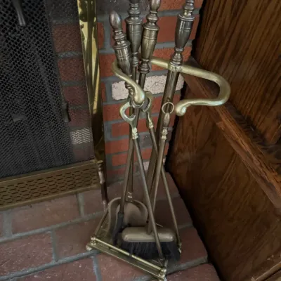 Sale Photo Thumbnail #177: Vintage brass fireplace tool set with decorative finial handles, including a shovel, brush, poker, and tongs on a matching stand.