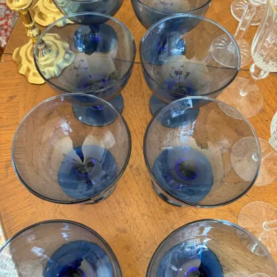Sale Photo Thumbnail #109: Set of eight vintage smoky blue glass goblets with short stems, displayed on a wooden tabletop.