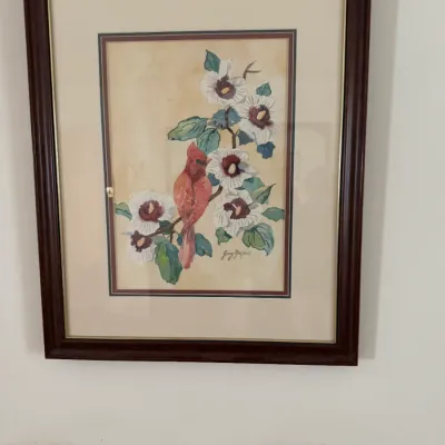 Framed watercolor painting depicting a red cardinal perched among white hibiscus flowers, signed by the artist and presented in a dark...