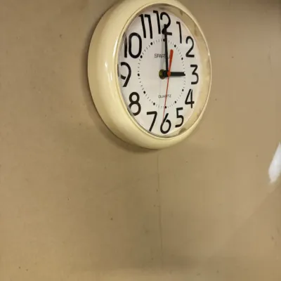 Vintage Spartus quartz wall clock with a cream-colored plastic frame and large, stylized black numerals.