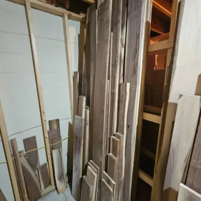 Assortment of raw hardwood lumber planks in various lengths and widths, suitable for woodworking projects.