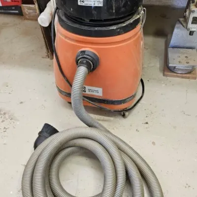 Vintage orange and black Tiger Tools wet/dry shop vacuum, model 9-55-13, with a long grey hose.
