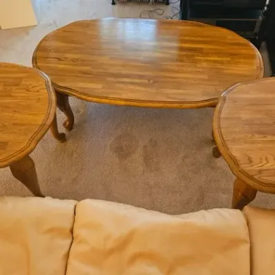 Three-piece traditional oak living room table set, including an oval coffee table and two matching end tables with scalloped edges and...