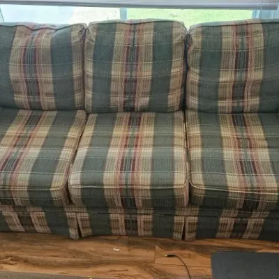Three-cushion sofa featuring a classic plaid upholstery pattern in shades of green, beige, and burgundy, with rolled arms and a skirted...