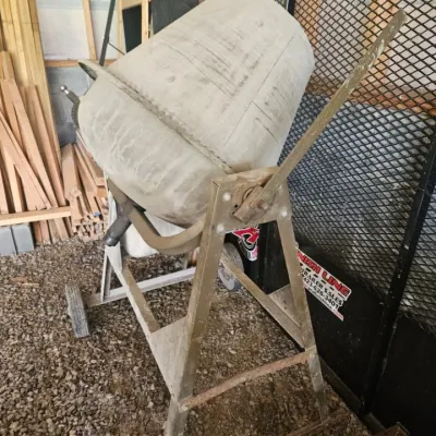 Portable electric cement mixer on a wheeled metal stand, showing signs of use with dried concrete residue.