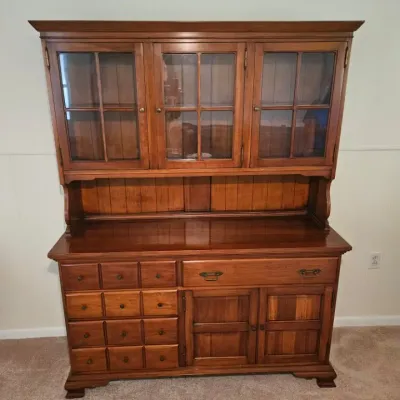 Vintage cherry wood hutch featuring a glass-front upper cabinet with three doors, an open display shelf, and a lower buffet base with...