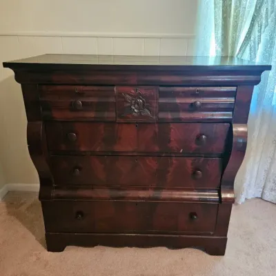Antique Empire-style mahogany veneer chest of drawers, featuring a curved ogee top drawer with a central carved floral motif, wooden...
