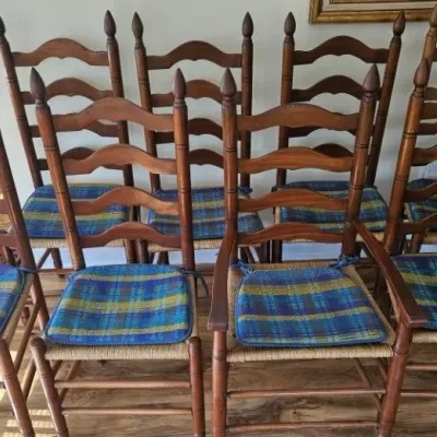 Set of eight vintage ladder-back dining chairs with rush seats, including one armchair, featuring turned finials and blue and yellow...