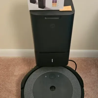 iRobot Roomba robot vacuum with its Clean Base automatic dirt disposal unit and a boxed set of dual-mode virtual wall barriers.