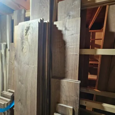 Large assortment of rough-cut walnut lumber planks in various lengths and widths, suitable for woodworking projects.