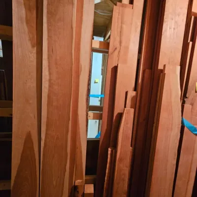 Large assortment of rough-cut cherry lumber boards in various lengths and widths, ideal for woodworking projects.