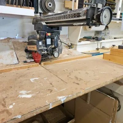 Vintage Sears Craftsman 10-inch radial arm saw mounted on a wooden workbench, showing signs of use and sawdust accumulation.
