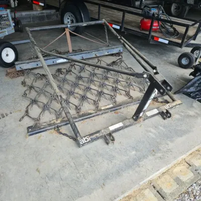 ABI Attachments chain harrow with a black metal lift frame, showing some wear from outdoor use.