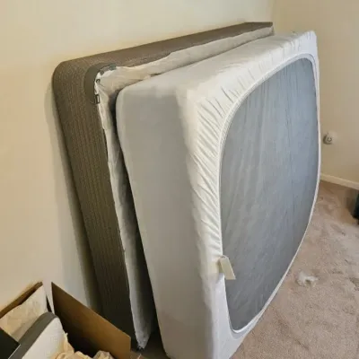 Modern queen-size mattress and matching box spring, shown leaning against a wall in clean, gently used condition.