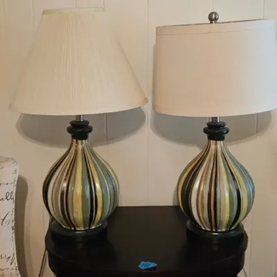 Pair of contemporary ceramic table lamps featuring a ribbed, teardrop-shaped base with vertical stripes in shades of green, gold, and...