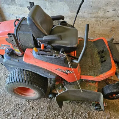 Kubota ZD323 zero-turn riding lawn mower, showing some wear and grass clippings from use.
