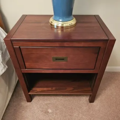 Contemporary cherry-finished wood nightstand featuring a single drawer with a recessed brass pull and an open lower shelf.