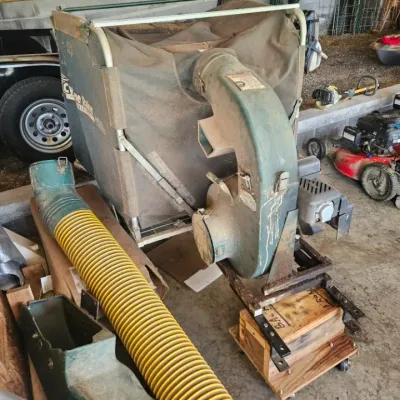Cyclone Rake tow-behind leaf vacuum system with collection bag, engine unit, and yellow corrugated hose, showing signs of moderate use.