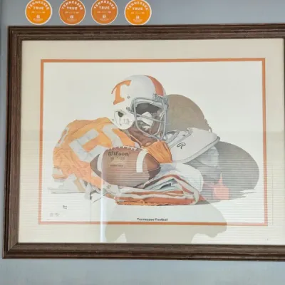 Framed Tennessee Football art print featuring a Volunteers helmet, jersey, and Wilson football, housed in a dark wood frame.