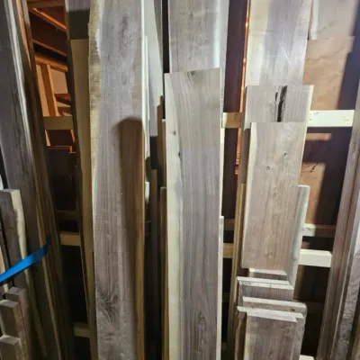 Assorted raw walnut lumber planks in various lengths and widths, suitable for woodworking projects.