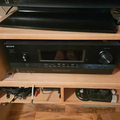 Sony digital audio/video control center receiver, housed in a light wood media console beneath a Panasonic television.