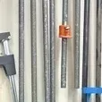 Assortment of vintage long pipe clamps hanging in a workshop, showing signs of use and wear.