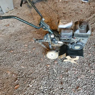 Gas-powered front-tine garden tiller with an OHV engine, showing some wear from outdoor use.