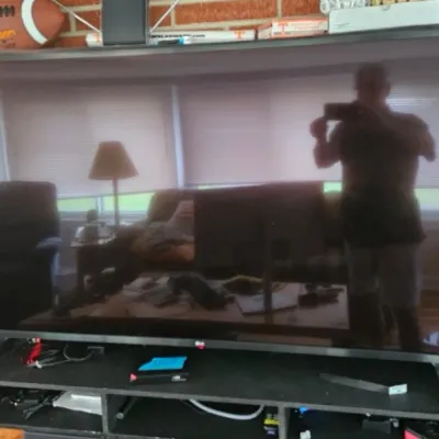 LG flat-screen television on a black media stand, showing a reflection of the room.
