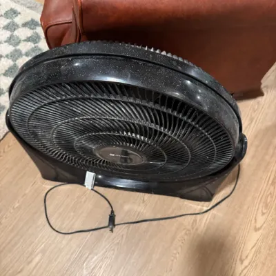 Utilitech black plastic floor fan with adjustable tilt, showing some dust from use.