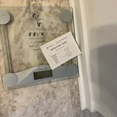 Sale Photo Thumbnail #124: Etekcity digital body weight scale with a clear tempered glass platform, accompanied by its original quick start guide.