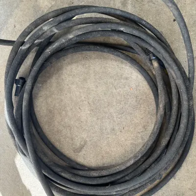 Sale Photo Thumbnail #238: Coiled black rubber garden hose showing signs of outdoor wear and dirt.