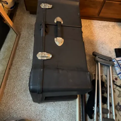 Sale Photo Thumbnail #141: Heavy-duty black plastic hard-shell utility case with metal latches and a carrying handle, shown alongside a pair of aluminum crutches.