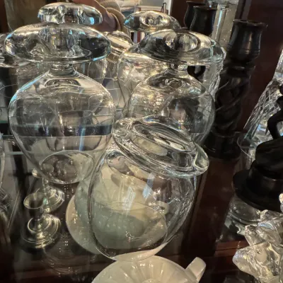 Sale Photo Thumbnail #252: Collection of clear glass stemware, including large balloon wine glasses, displayed upside down on a mirrored shelf alongside other decorative glassware.