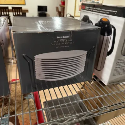 World Market 10.5-inch stacking dinner plate set in its original box, alongside an Oggi thermal carafe set on a wire shelf.