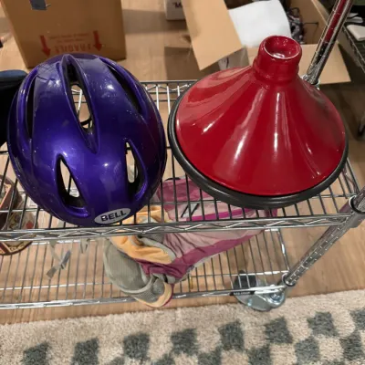 Sale Photo Thumbnail #117: Purple Bell bicycle helmet and a red ceramic tagine pot displayed on a wire shelving unit.