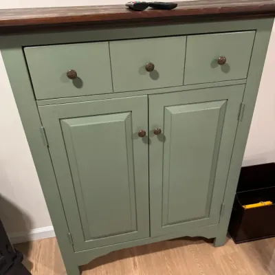 Sage green painted wooden cabinet featuring three top drawers, a double-door lower compartment, and a contrasting dark wood top surface.