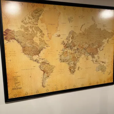 Large framed world map with an antique-style sepia finish, housed in a simple black frame.
