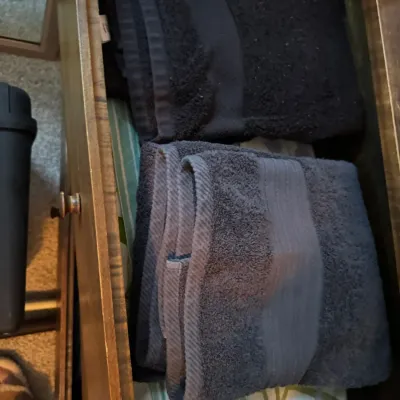 Sale Photo Thumbnail #145: Two folded dark gray bath towels stored inside a wooden dresser drawer.