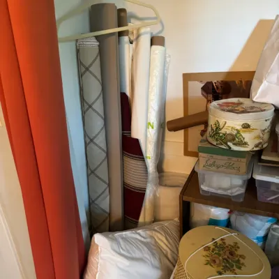 Sale Photo Thumbnail #191: Assorted rolls of fabric and sewing supplies stored in a closet, including a vintage woven sewing basket with a floral lid.