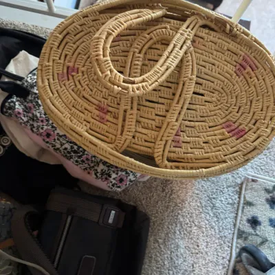 Sale Photo Thumbnail #161: Vintage woven straw basket with dual handles and pink accents, shown alongside a black Tumi shoulder bag.