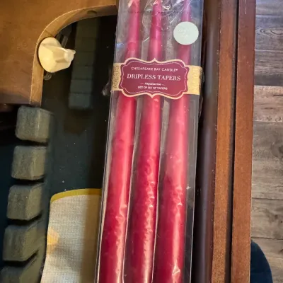 Sale Photo Thumbnail #224: Unopened package of Chesapeake Bay Candle dripless taper candles in a vibrant pink or magenta hue, resting inside a wooden drawer.