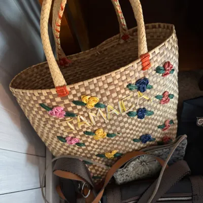 Sale Photo Thumbnail #160: Vintage woven straw tote bag featuring embroidered floral details and "Jamaica" lettering, shown alongside other modern handbags.