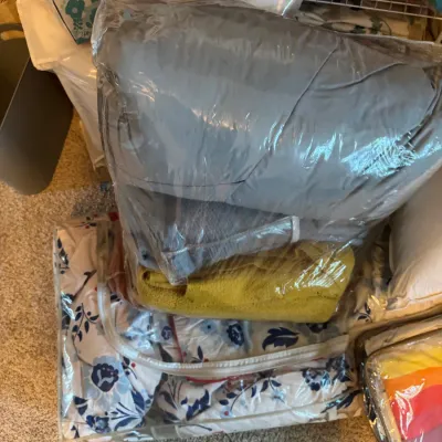 Sale Photo Thumbnail #186: Assorted bedding and linens, including a floral comforter and solid-colored blankets, stored in clear zippered plastic bags.
