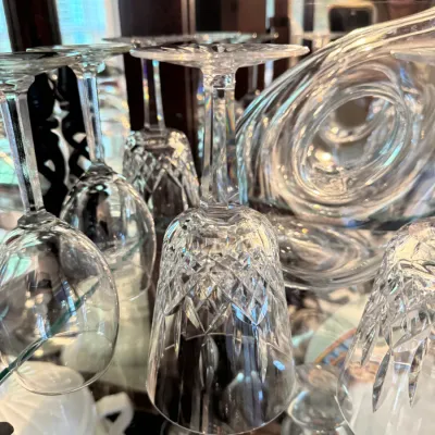 Collection of cut crystal stemware, including wine glasses and goblets, displayed upside down on a glass shelf.
