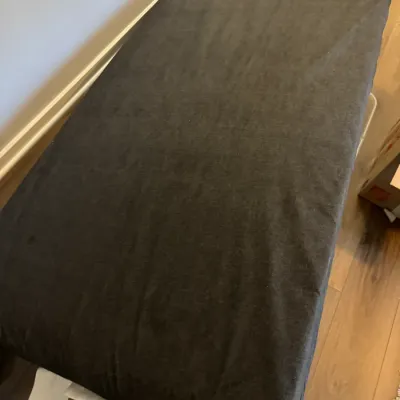 Sale Photo Thumbnail #128: Twin-size mattress with a dark gray fitted sheet, resting on a frame in a room with hardwood floors.