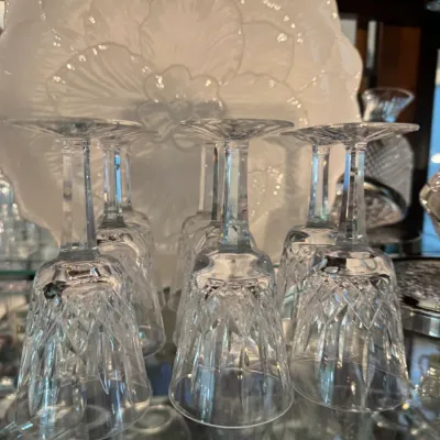 Sale Photo Thumbnail #247: Collection of cut crystal stemmed glassware displayed upside down, with a white floral-patterned ceramic plate in the background.