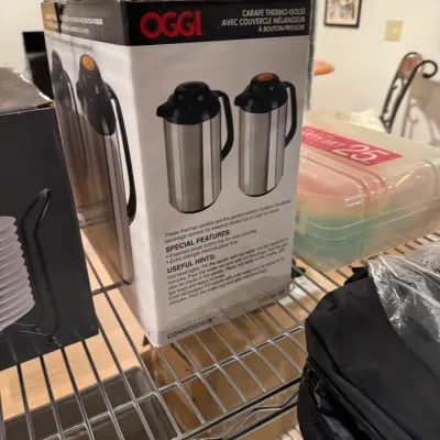 Oggi Connoisseur thermal carafe in its original box, featuring a stainless steel body and black press-button top.