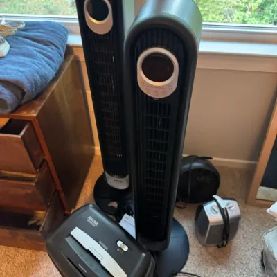 Two black Lasko tower fans shown alongside an Aurora paper shredder and a small space heater.