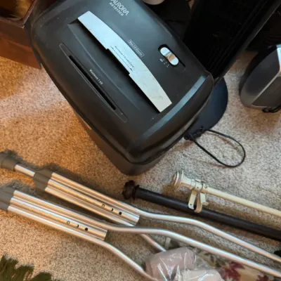 Sale Photo Thumbnail #139: Aurora AS1015CD 10-sheet paper shredder, shown alongside a pair of aluminum crutches and curtain rods on a carpeted floor.