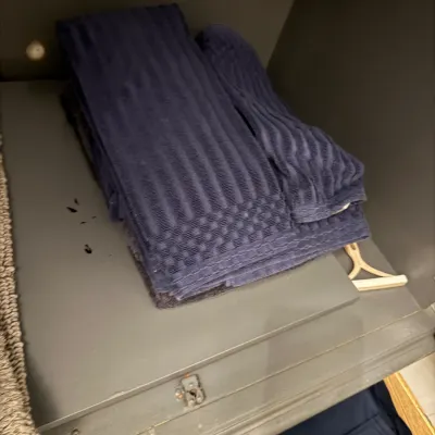 Sale Photo Thumbnail #182: Folded navy blue ribbed bath towels and hand towels stacked on a grey shelf.